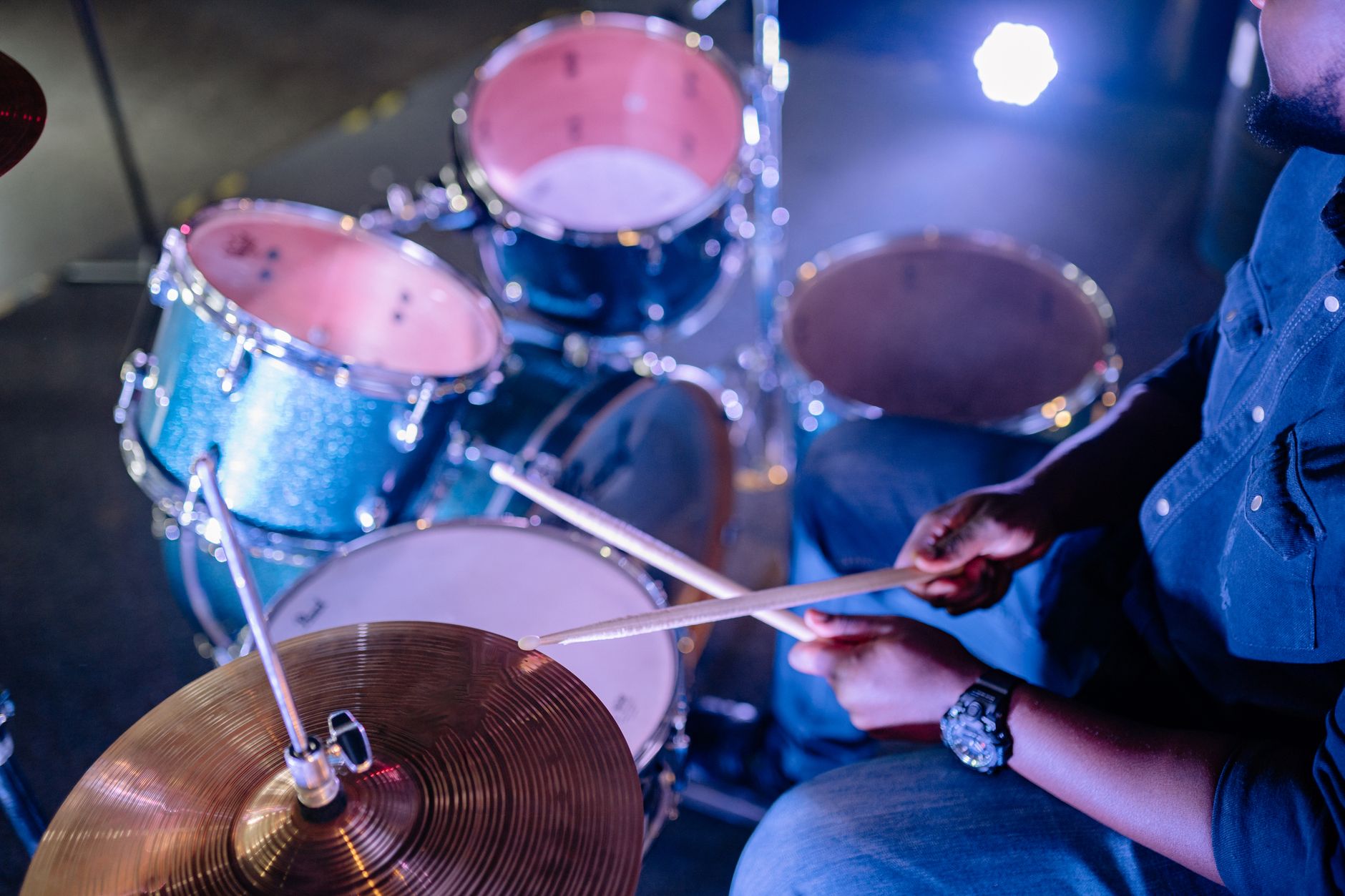 Mains d'un batteur et baguettes en mouvement sur une batterie.